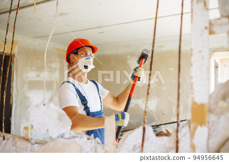 Young male builder in hard hat holding tools. Apartment repair and renovation concept. Young male builder in hard hat holding tools. Apartment repair and renovation concept. 94956645