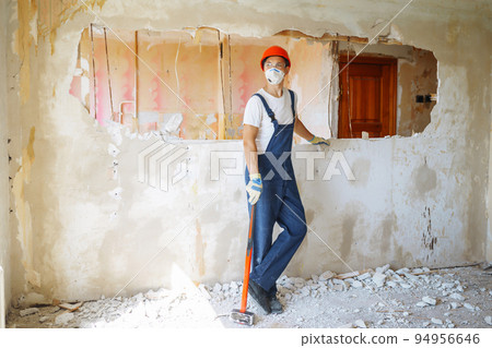 Young male builder in hard hat holding tools. Apartment repair and renovation concept. Young male builder in hard hat holding tools. Apartment repair and renovation concept. 94956646