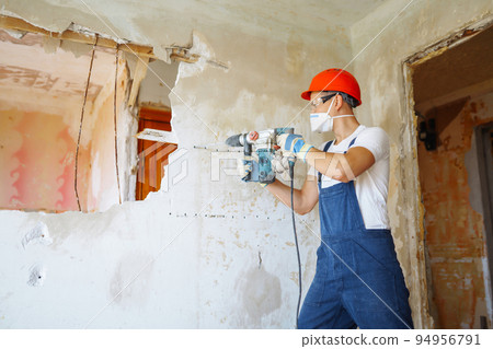 Repairer in boilersuit holding tools. Apartment repair and renovation concept. Building. Repairer in boilersuit holding tools. Apartment repair and renovation concept. Building. 94956791