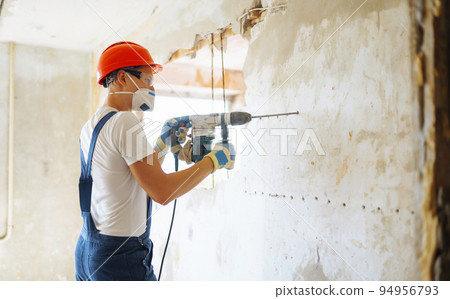 Repairer in boilersuit holding tools. Apartment repair and renovation concept. Building. 94956793