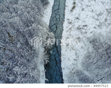 Snowy forest and curvy river on the plain in winter. Aerial view of nature in winter 94957521