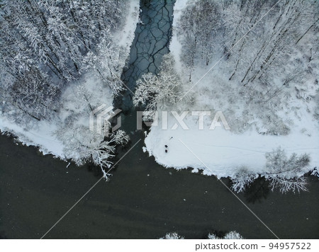 Snowy forest and curvy river on the plain in winter. Aerial view of nature in winter Snowy forest and curvy river on the plain in winter. Aerial view of nature in winter 94957522