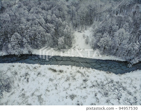 Snowy forest and curvy river on the plain in winter. Aerial view of nature in winter Snowy forest and curvy river on the plain in winter. Aerial view of nature in winter 94957530