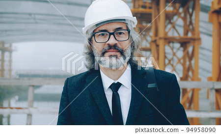 portrait of successful mature man architect wearing safety helmet standing in construction area alone and looking at camera 94958090