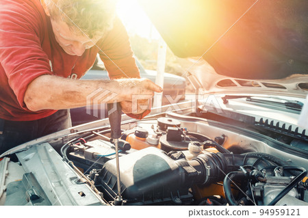 The concept of disability of people and their adaptation to life. A blond disabled man repairs a car, works with a screwdriver. Disabled from childhood. Horizontal. Light The concept of disability of people and their adaptation to life. A blond disabled man repairs a car, works with a screwdriver. Disabled from childhood. Horizontal. Light 94959121