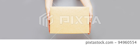human hands holding delivers carton box on grey background. Delivery and online shopping concept. 94960554