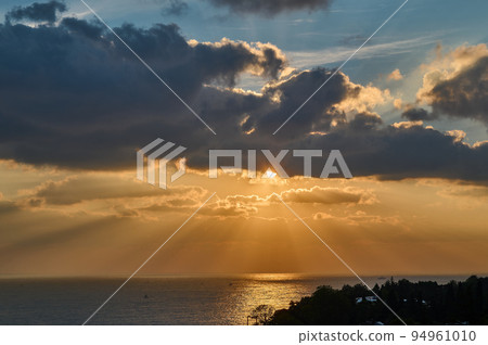 Sun rays from clouds at sunset over the sea 94961010