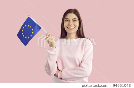Happy smiling female European Union citizen waving small EU flag on pink background. Happy smiling female European Union citizen waving small EU flag on pink background. 94961048