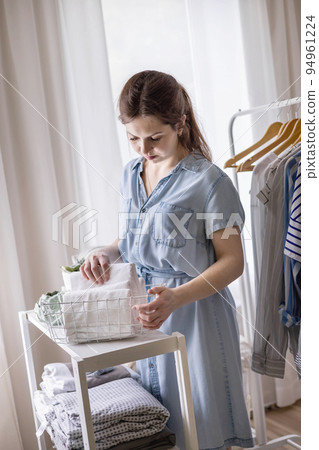 Modern housewife putting neatly folded towels, pillowcases, duvet covers into plastic metallic case Modern housewife putting neatly folded towels, pillowcases, duvet covers into plastic metallic case 94961224