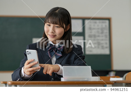 一個高中女生在學校教室裡操作智能手機 94961251