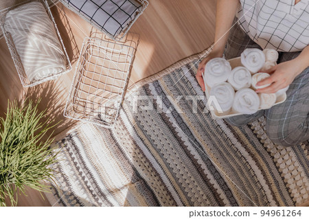 Modern housewife putting neatly folded towels, pillowcases, duvet covers into plastic metallic case Modern housewife putting neatly folded towels, pillowcases, duvet covers into plastic metallic case 94961264