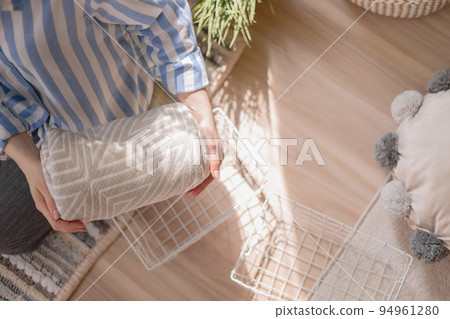Modern housewife putting neatly folded towels, pillowcases, duvet covers into plastic metallic case Modern housewife putting neatly folded towels, pillowcases, duvet covers into plastic metallic case 94961280