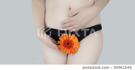 Virginity. Menstruation. Critical days. Concept photo. The girl holds a flower in the crotch area, symbolizing the hymen, critical days and gynecological problems. 94961648