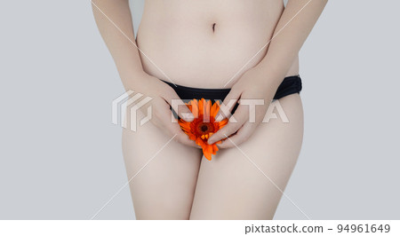 Virginity. Menstruation. Critical days. Concept photo. The girl holds a flower in the crotch area, symbolizing the hymen, critical days and gynecological problems. 94961649