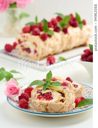 Baked meringue roll with cream and fresh red raspberry, white background Baked meringue roll with cream and fresh red raspberry, white background 94962088