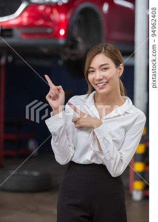 portrait asian woman smile finger pointing empty space standing at service engine. portrait asian woman smile finger pointing empty space standing at service engine. 94962408