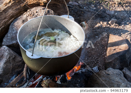 Boiling cauldron hangs over an open fire, Boiling cauldron hangs over an open fire, 94963179