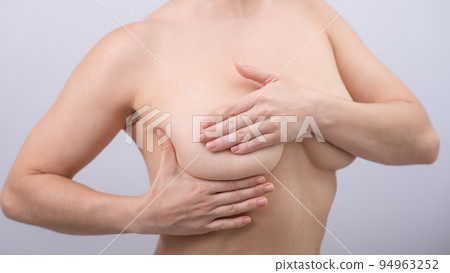 Caucasian woman self checks for breast cancer on white background.  94963252