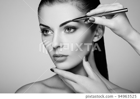 Beautiful brunette woman paints the eyebrows 94963525