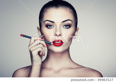 Beautiful woman paints lips with lipstick 94963527