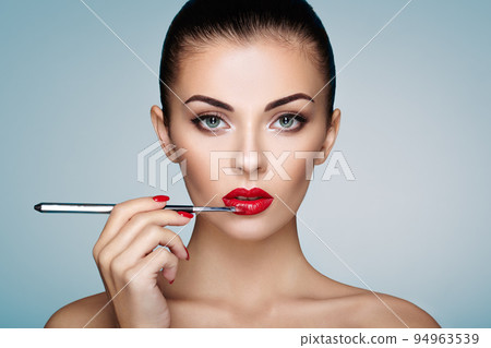 Beautiful woman paints lips with lipstick 94963539
