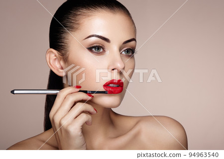 Beautiful woman paints lips with lipstick 94963540