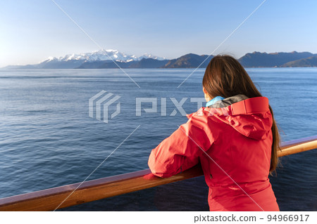 Alaska cruise travel tourist looking at mountains landscape from balcony deck of ship. Inside passage Glacier bay scenic vacation travel woman enjoying scenery from boat 94966917