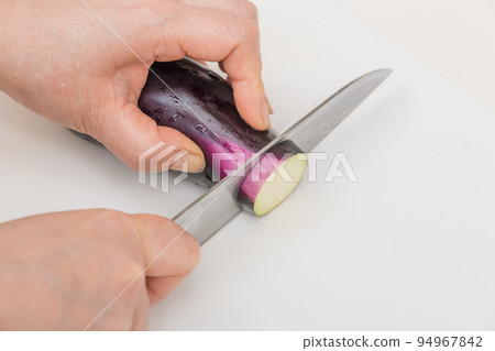 [A middle-aged housewife slices an eggplant with a Santoku knife] 94967842