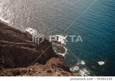 View from above of a volcanic cliff over the sea View from above of a volcanic cliff over the sea 94968189