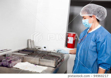 Female scientist staining microscope slides for cytology studies in the laboratory. 94968217