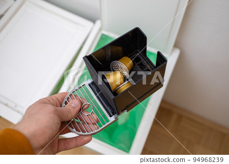 throwing coffee capsules in the trash bin 94968239