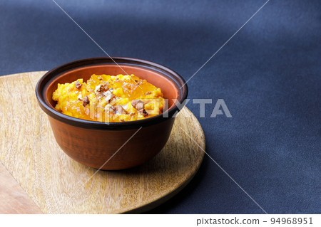 Sweet pumpkin porridge in clay bowl with jam and nuts Sweet pumpkin porridge in clay bowl with jam and nuts 94968951