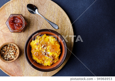Sweet pumpkin porridge in clay bowl with jam and nuts 94968953