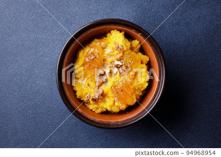 Sweet pumpkin porridge in clay bowl with jam and nuts Sweet pumpkin porridge in clay bowl with jam and nuts 94968954