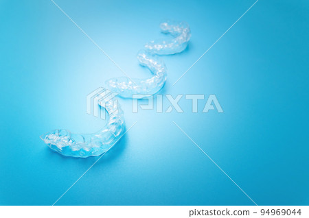close-up, new transparent braces lie in a row on a blue background. suitable for dental clinic banner close-up, new transparent braces lie in a row on a blue background. suitable for dental clinic banner 94969044