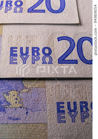 This is a twenty euro note macro image of a blue color banknote. The note has the European Union symbol on it, along with other symbols that represent economics 94969054