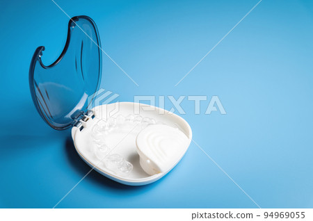 orthodontic care, new invisible plastic aligners printed on a 3d printer lie in a special white box, on a blue background without people orthodontic care, new invisible plastic aligners printed on a 3d printer lie in a special white box, on a blue background without people 94969055