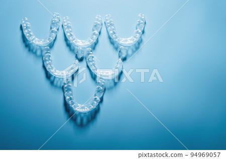 invisible plastic braces lie in a pyramid shape in a row on a blue background, studio shot, nobody invisible plastic braces lie in a pyramid shape in a row on a blue background, studio shot, nobody 94969057