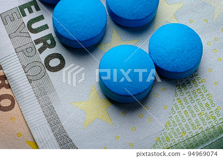 Blue tablets pill macro on 100 euro bill. Drug abuse Blue tablets pill macro on 100 euro bill. Drug abuse 94969074