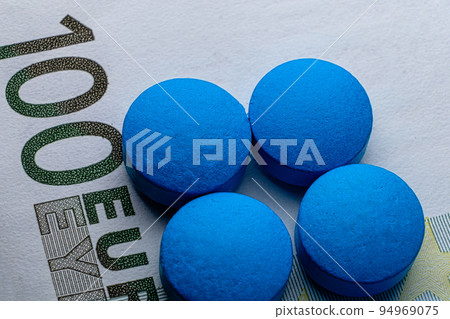 Healthcare. Blue tablets pill macro on 100 euro bill. Drug abuse 94969075
