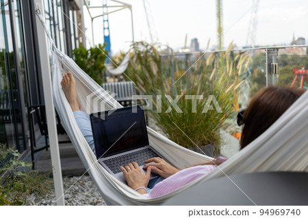 young woman freelancer working in hammock on terrace 94969740