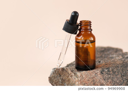 Cosmetic amber glass dropper bottle on wooden podium with pampas grass in soft focus. Oil, serum, fruit peeling. Natural beauty product presentation, pastel background. Front view. Mockup concept  94969908