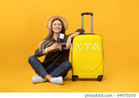Woman Sitting Near Suitcase Holding Travel Tickets On Yellow Background 94970250