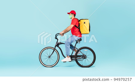 Guy With Yellow Backpack Delivering Food Riding Bike, Blue Background 94970257