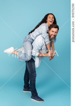 Laughing young european male holding on back middle eastern woman, have fun together, enjoy free time 94970290