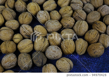 Peeled walnuts. Many closed nuts scattered on a blue background Peeled walnuts. Many closed nuts scattered on a blue background 94970428