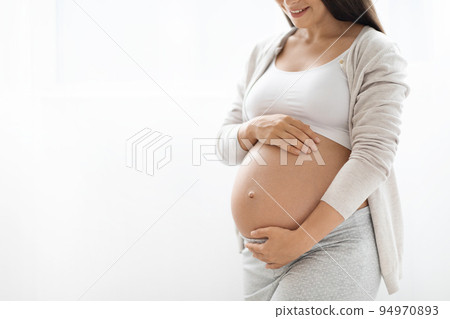 Cropped of pregnant woman touching her big belly Cropped of pregnant woman touching her big belly 94970893