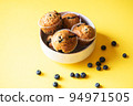 Blueberry muffins served in a bowl on a yellow background. Overhead view. 94971505