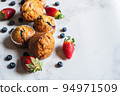 Blueberry and strawberry muffins with berries on a marble background. Close up and copy space. 94971509