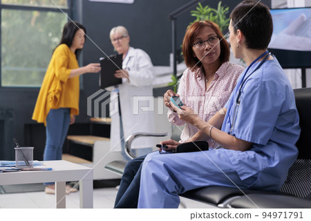 Medical assistant measuring insulin and glucose level with glucometer, doing health examination with diabetic old asian patient. Using insturment to check blood sample, diabetes consultation. 94971791